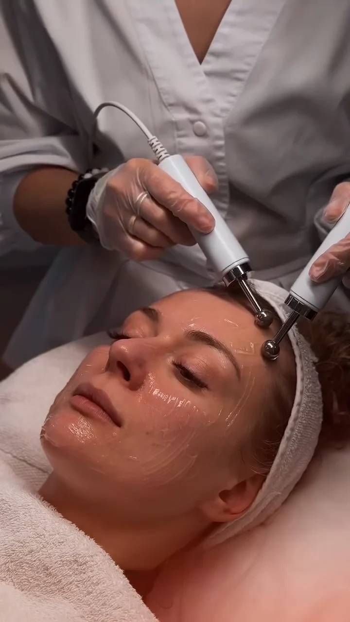 Paired facial instruments moving across gel-covered skin.